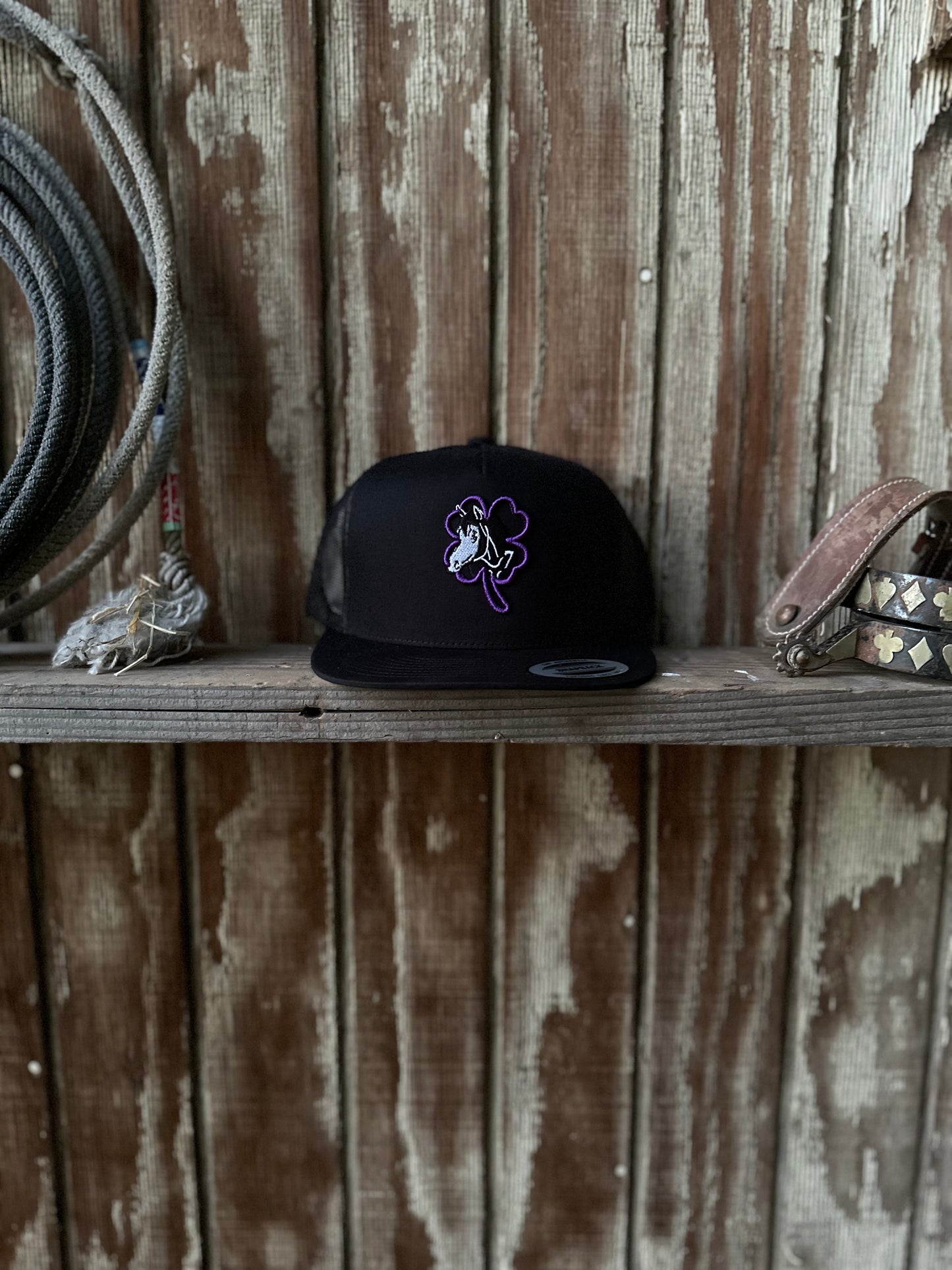 All black Cap Purple clover logo